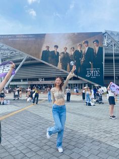 a woman holding up a purple kite in front of a large poster on the side of a building