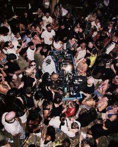 a large group of people standing around a dj booth