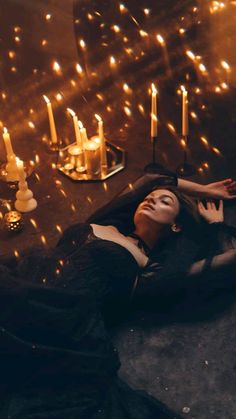 a woman laying on the ground in front of candles