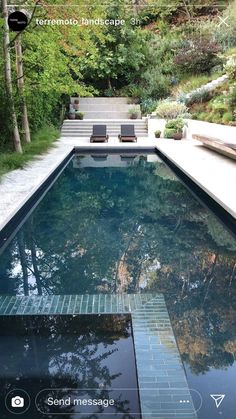 an outdoor swimming pool surrounded by greenery and stone steps with lounge chairs on the side