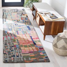 a multicolored rug on the floor next to a coffee table and plant in a living room