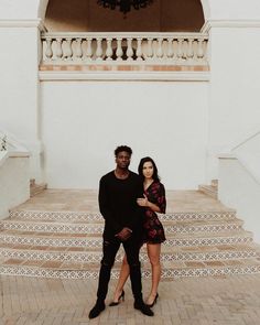 a man and woman standing in front of some stairs