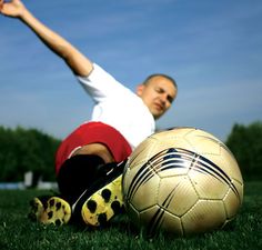 a man is sitting on the grass with a soccer ball in front of his feet