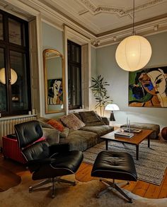 a living room filled with furniture and a painting on the wall next to a window