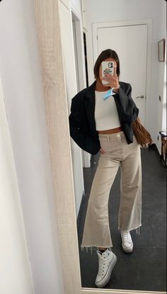 a woman taking a selfie in the mirror with her cell phone and jacket on