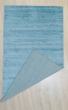 two pieces of blue rug sitting on top of a wooden floor