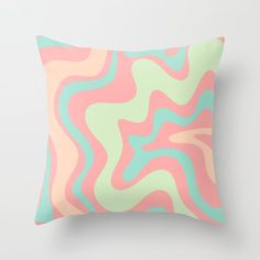 a pink, green and blue pillow with wavy lines on the front in pastel colors