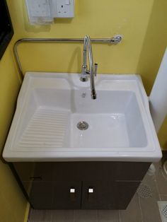 a white sink sitting under a faucet next to a wall mounted soap dispenser