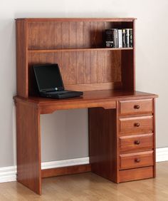 a laptop computer sitting on top of a wooden desk next to a book shelf with drawers