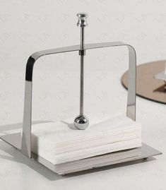 a stack of napkins sitting on top of a metal stand next to a plate