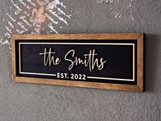 a wooden sign that says the smiths est 2020 hanging on a wall with graffiti behind it