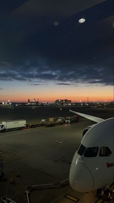 an airplane is parked on the tarmac at night with dark clouds in the background