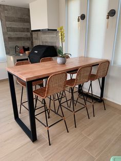 a kitchen table with four chairs and a potted plant on the counter in front of it