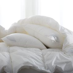 a pile of pillows sitting on top of a bed