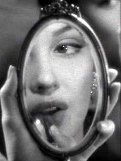 a woman looking into a magnifying glass with her face reflected in the mirror