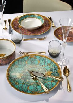 a table set with plates, silverware and wine glasses