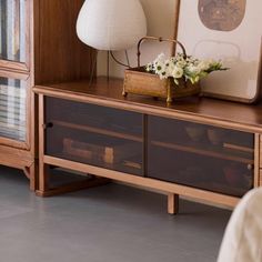 a wooden shelf with drawers and a lamp on top, in front of a bookcase