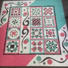 a quilt is laying on the floor next to a table cloth with circles and dots