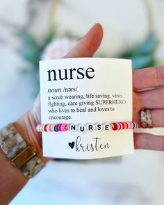 a person holding up a card with the words nurse on it and two bracelets