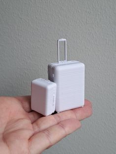 a miniature white piece of luggage in someone's hand