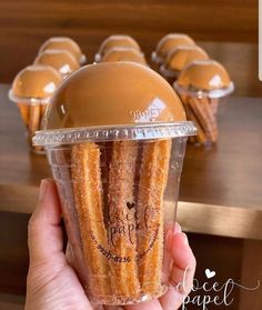 a person holding up a plastic cup filled with churros