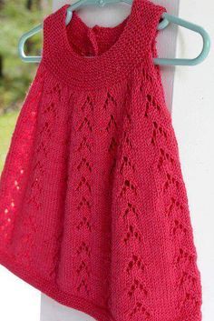 a red knitted sweater hanging on a clothes line with an iron hook in the foreground