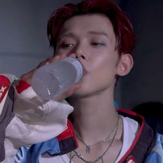 a man with red hair drinking from a bottle