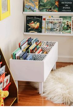 a book shelf filled with lots of books on top of a wooden floor next to a white rug