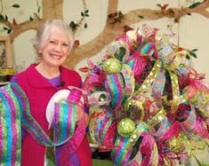 an older woman standing next to a wreath with ribbons on it and holding a roll of toilet paper