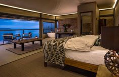 a bedroom with a large bed sitting next to a window overlooking the ocean at night