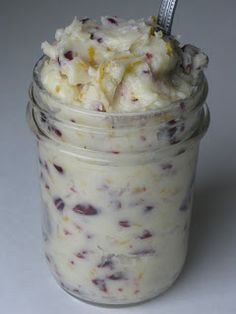 a glass jar filled with ice cream on top of a white table next to a spoon