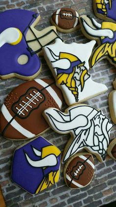 decorated cookies are arranged on a brick wall to look like footballs, helmets and other sports related items