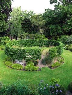 an aerial view of a circular garden in the middle of a lawn with trees and bushes surrounding it