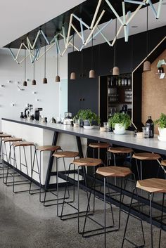 a bar with several stools and lights hanging from the ceiling above it, along with potted plants