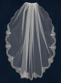 a white veil with lace on it is hanging in front of a black background,