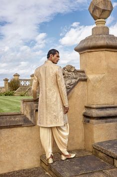 This set features lurex ribbon embroidery in an abstract pattern. It is paired with a matching silk kurta and silk dhoti salwar.From Seema Gujral's A Royal Affair collection. DELIVERY TIMEPlease allow 8-12 weeks for your outfit to arrive. FABRIC DETAILSSherwani- Raw SilkKurta - SilkAfghani Salwar -Silk Professional cleaning only. Gold Silk Bandhgala For Wedding, Festive Silk Bandhgala For Wedding, Gold Silk Sherwani For Festive Season, Gold Silk Sherwani For Festive Occasions, Festive Silk Bandhgala With Naqshi Details, Festive Silk Bandhgala With Naqshi, Silk Sherwani With Zari Work And Traditional Drape, Gold Silk Sherwani For Eid, Gold Bollywood Sherwani For Festive Occasions