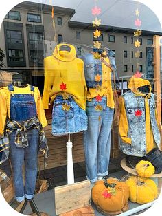 two denim jackets and pumpkins are on display in a store window with autumn decorations