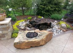 an outdoor fire pit surrounded by rocks and plants