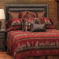 a bed with pillows and blankets on top of it next to a brick wall in front of a window