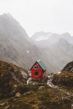 a small red house sitting on top of a lush green hillside