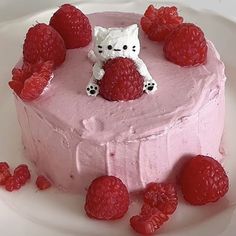 a cake decorated with raspberries and a hello kitty figurine on top