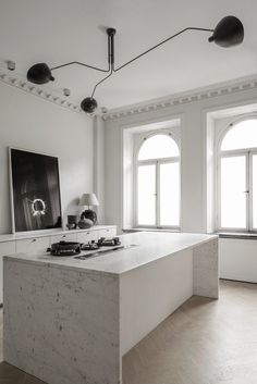 an empty room with two large windows and a white counter top in front of it