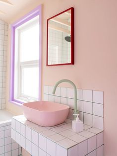 a pink bowl sink sitting on top of a white counter next to a window in a bathroom