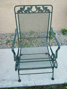 a green metal chair sitting on top of a sidewalk