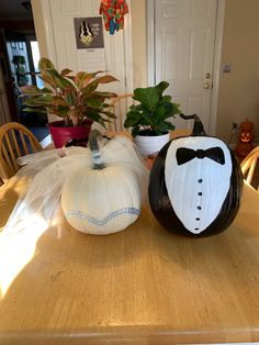 two pumpkins with tuxedo and bow ties sitting on top of a table