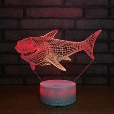 a red shark lamp sitting on top of a wooden table next to a brick wall