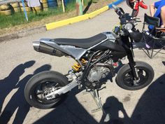 a motorcycle parked on the side of a road next to a person sitting in a chair