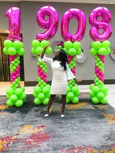 a woman standing in front of balloons that spell out the number 909, with her arms outstretched