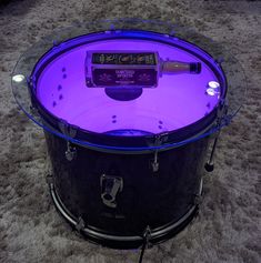 a drum is lit up with purple light in the middle of carpeted flooring