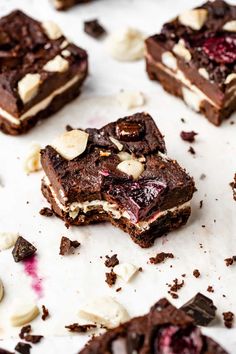 several pieces of dessert sitting on top of a white tablecloth covered in nuts and chocolate